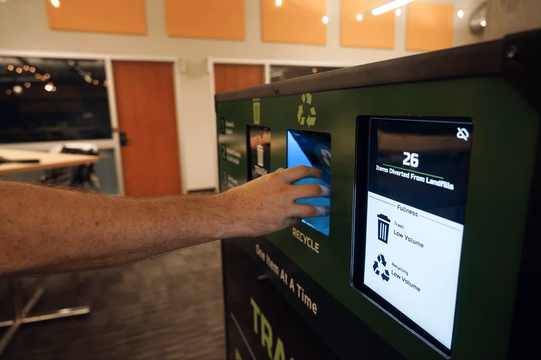 Someone putting an item into a MyMatR unit with a display screen showing 26 total deposits